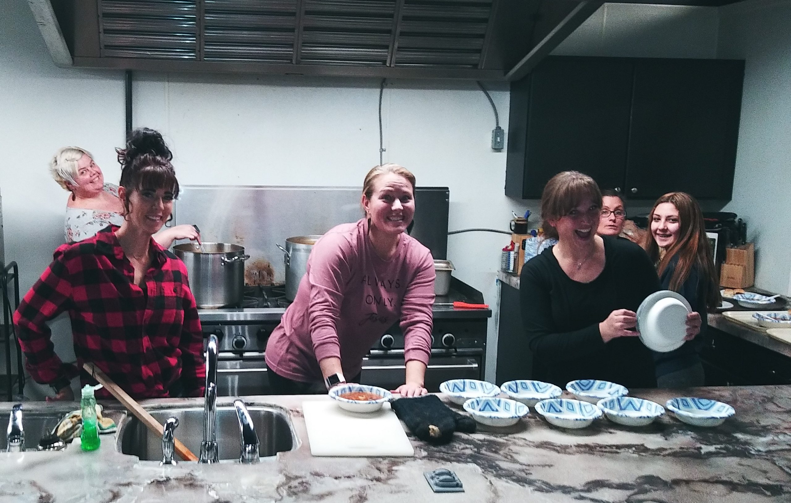 Three women in a kitchen preparing food.